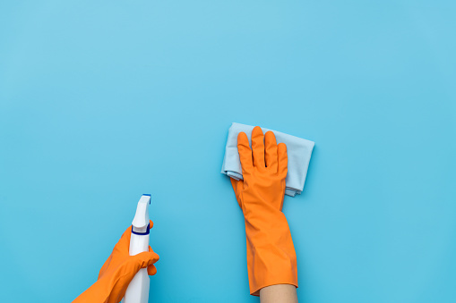 Woman hand cleaning blue wall with rag.