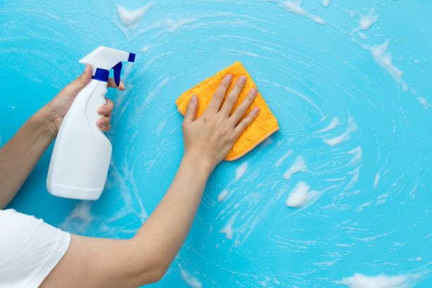 istock Woman hand cleaning blue wall with rag and spray bottle 1410844031