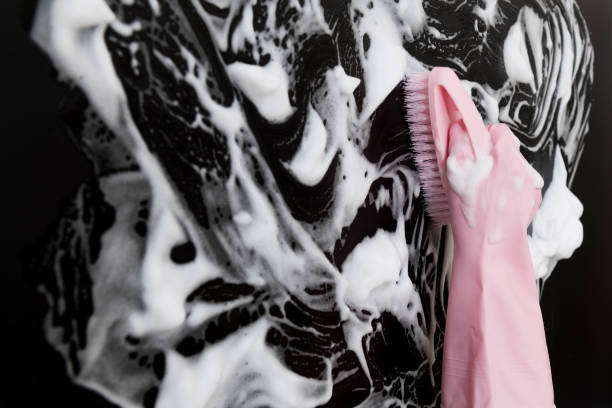 Woman hand cleaning blue wall with brush.
