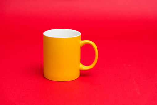 Yellow mug on red background.