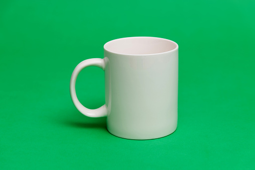 White mug on green background.