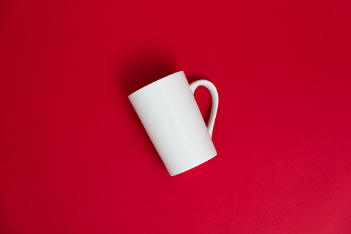 White mug on red background.