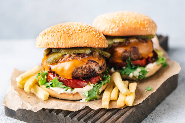 delicious juicy cheeseburgers served with french fries - arugula freshness food herb imagens e fotografias de stock