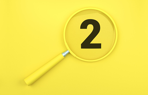Yellow magnifying glass over number 2 on yellow background.