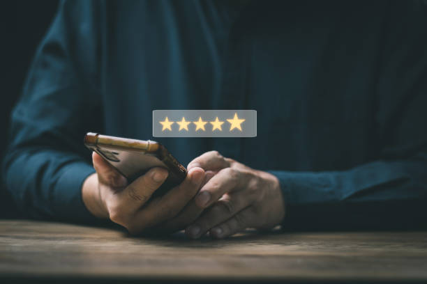 istock Customer Satisfaction Survey Concept, A man's hand using a smartphone gives a 5 star rating to show the highest level of satisfaction with excellent service.. 1410846366