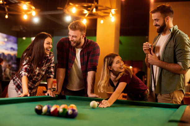 istock Group of friends having fun while playing pool in a local pool hall 1410850492