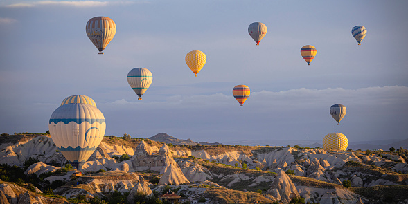 GOREME/TURKEY - June 27, 2022: colorful hot air balloons fly at sunrise near goreme