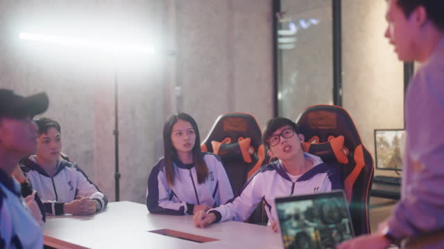 Asian Chinese Esport Team listening to Coach analysing briefing strategy before grand final videogame competition in meeting room