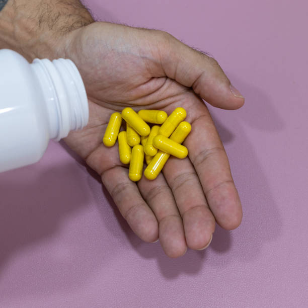 Hands holding yellow capsules, curcuma, berberine.