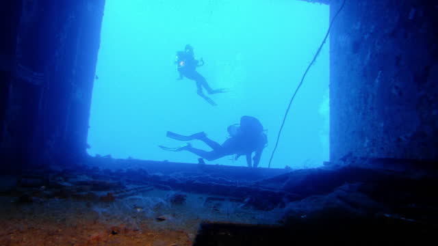 Exploring famous diving spot in Red Sea. Divers silhouettes above Salem Express ship wreck