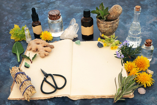 Open old hemp recipe notebook, natural pagan wiccan herbal plant and flower  remedy preparation. Herbs, flowers, crystals, aromatherapy essential oils and smudge stick. Nature still life.