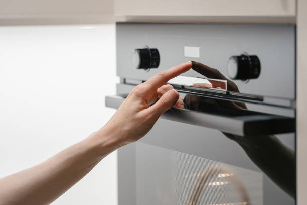 istock Woman press button on touchscreen display at modern electric oven 1410861420