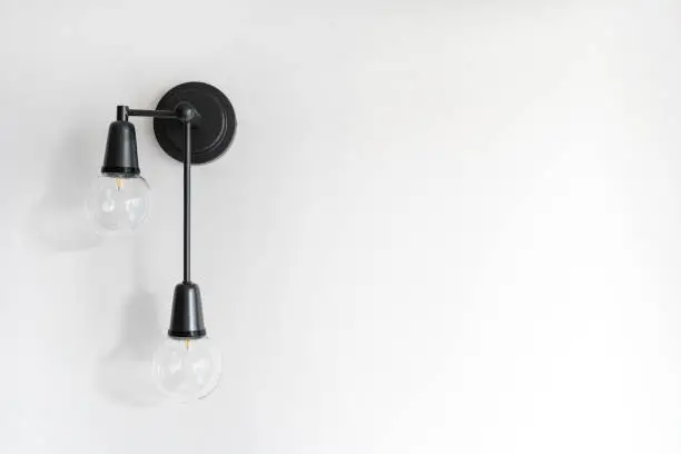 Energy saving lamp in black metal sconce on copy space wall. Electricity and illumination in living room. Light bulb in modern loft style apartment. Concepts of power equipment and household fixture