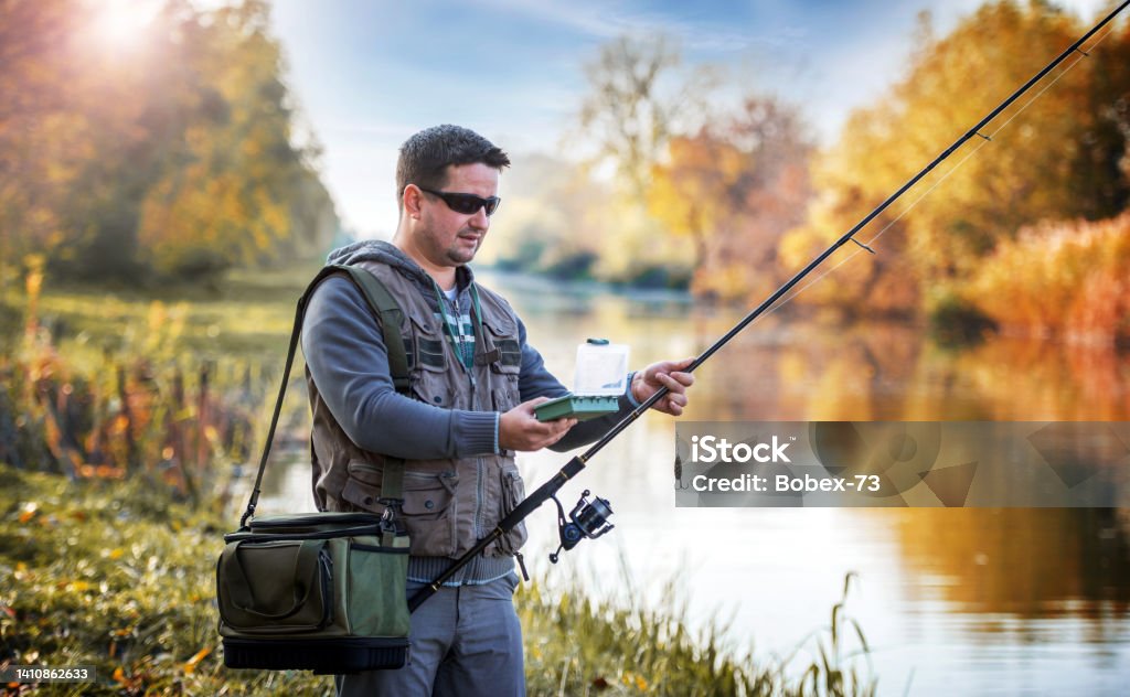 Angler choosing bait while trying to catch a trophy fish on the river. Sport and recreation concept Angling on the river. Fisherman choosing bait while trying to catch a trophy fish. Sport and recreation concept Fishing Stock Photo