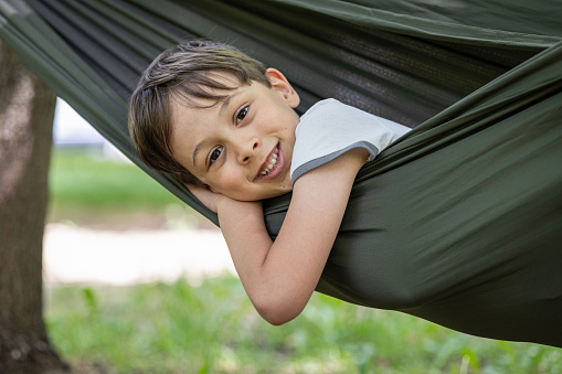 Little boy smiling and looking at camera while laying in a hammock