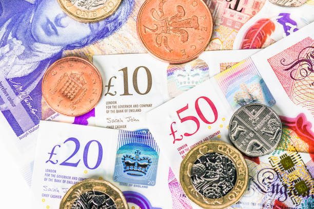 Modern British coins and banknotes Close-up of a collection of modern polymer UK banknotes, along with one pound coins and other change. british currency stock pictures, royalty-free photos & images