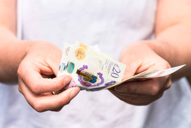 Counting out UK cash Close-up as a woman counts out modern British banknotes. british currency stock pictures, royalty-free photos & images