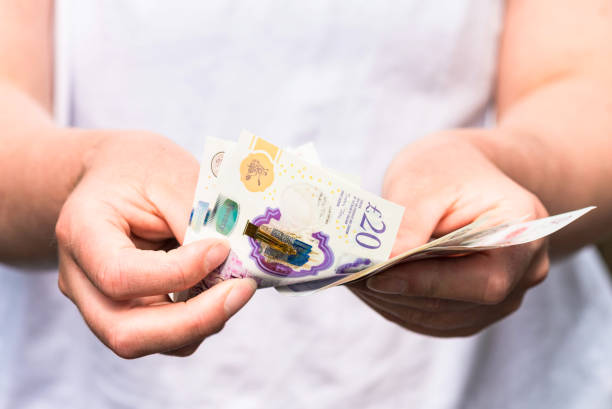 Counting out UK cash Close-up as a woman counts out modern British banknotes. counting coins stock pictures, royalty-free photos & images