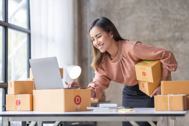 SME SME Online seller Young Asian woman working on laptop and box checking online order, check goods stock delivery package shipping postal. Asian woman startup SME small business at home office mecklenburg vorpommern photos stock pictures, royalty-free photos & images