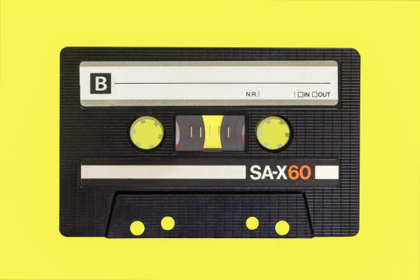 istock Vintage cassette tape isolated. Black audio cassette B side on yellow background. 1410868157