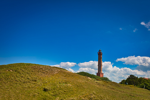 Lighthouse in the dunes of Norderney island with blue sky and some clouds