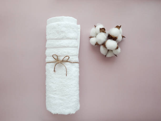 istock Twisted whte towel with cotton flowers on the light background 1410871260