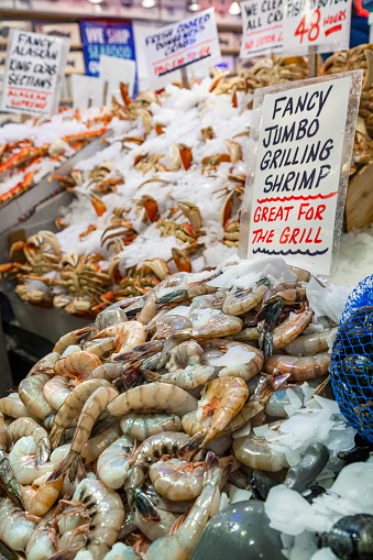Vendor stands at a seafood stand at the Pike Place Market in Seattle Washington USA in the afternoon.