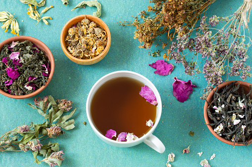 Herbal tea with flower petals and dried herbs in bunches and bowls. Dried and fermented plants for delicious drinks, herbal medicine and health promotion