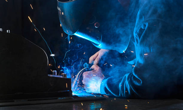 Industrial welder Shot of an industrial worker wearing safety helmet welding metal with sparks at factory automatic welding torch stock pictures, royalty-free photos & images