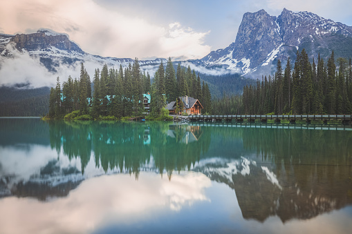 A misty, atmospheric sunrise or sunset over traditional log cabin and beautiful Rocky Mountain landscape at Emerald Lake, B.C., Canada near Field British Columbia, in Yoho National Park.