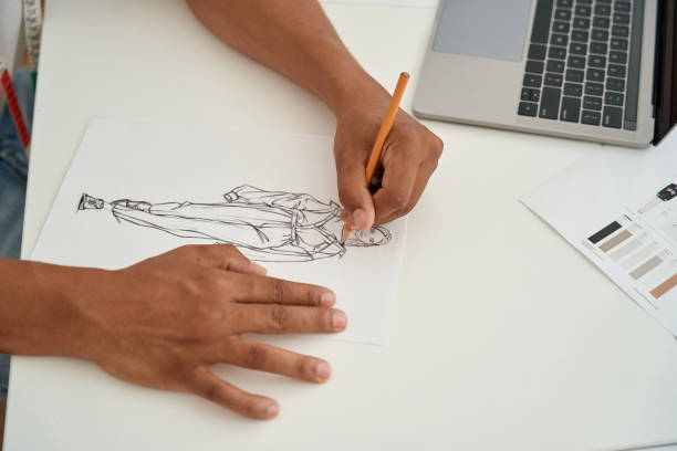 istock Fashion designer creating clothes on paper before laptop 1410874725