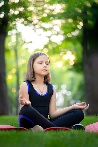 meditation in the park in the lotus position little girl meditates and relaxes