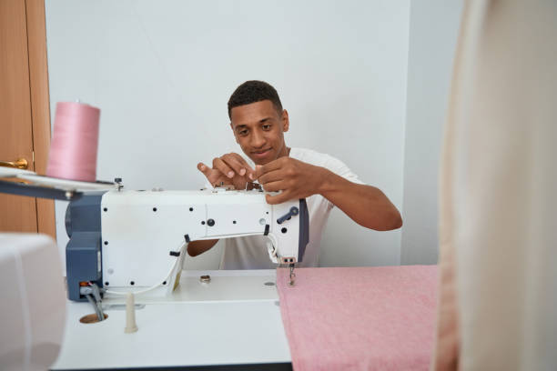 istock Smiling young tailor enjoying work in atelier with equipment 1410874746