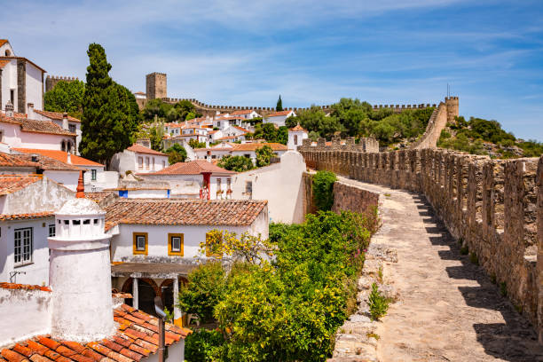 The castle and towers of the historic old town of Obidos with the city walls you can walk through, Portugal On the idyllic walkable city wall around the historic old town of Obidos in western Portugal obidos photos stock pictures, royalty-free photos & images