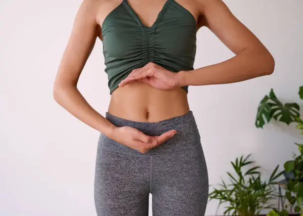 Photo of Cropped shot of a young multi-ethnic woman's stomach cupped by her hands