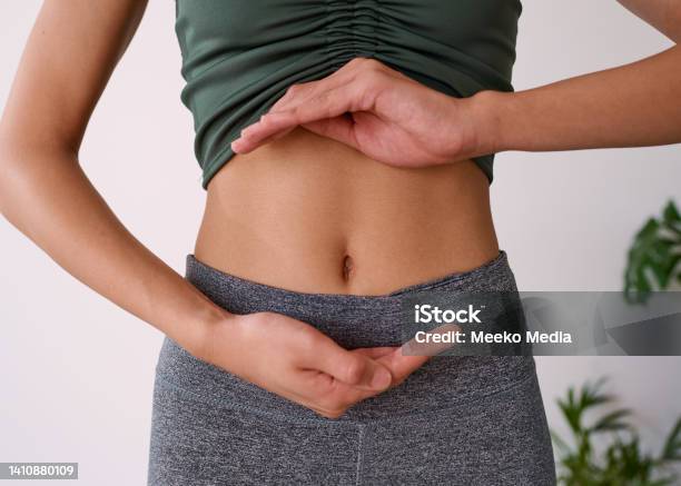 Close Up Of A Young Multiethnic Womans Stomach Cupped By Her Hands Stock Photo - Download Image Now