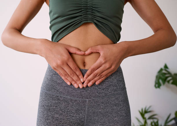 primo piano delle mani di una donna multietnica sullo stomaco - bassiera foto e immagini stock