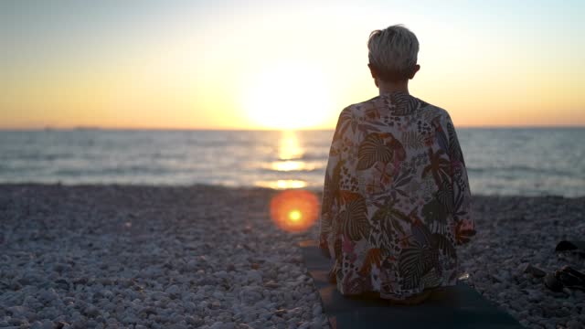 Yoga instructor meditating on the beach. the woman watching the sun rise.doing yoga when the sun rising.