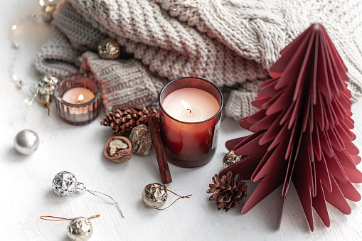 Cozy winter composition with burning candles, knitted element and decorative details.
