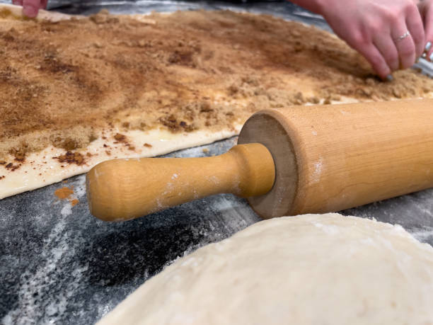 Making Cinnamon rolls. Wood rolling pin, dough, and ingredients. stock photo