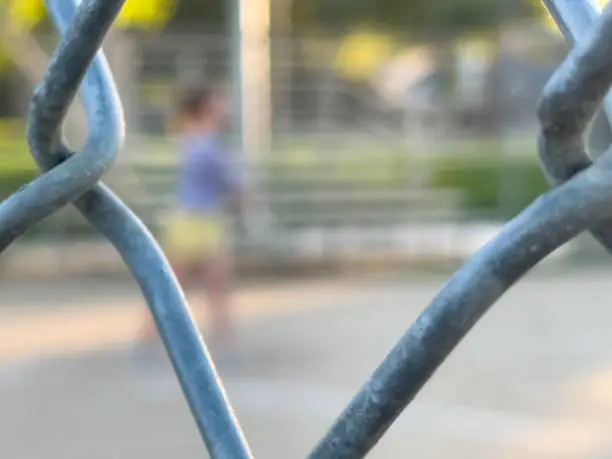 Spectators view of softball game through chainlink fence