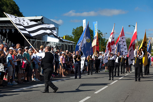 Quimper, France - July 24 2022: Flag bearers presenting the different banners of the Breton countries during the Cornouaille festival.