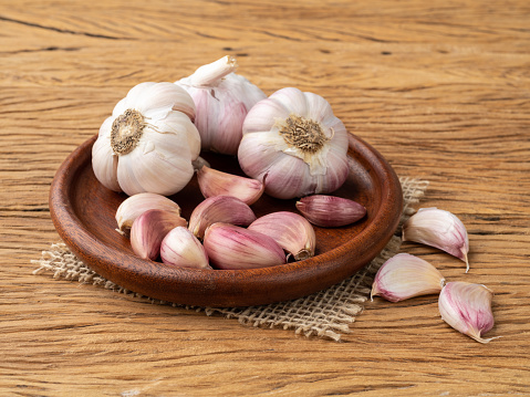 Garlic bulb and cloves on a plate over wooden table.