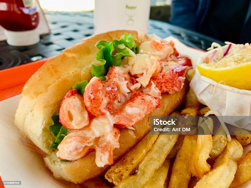 Fresh Maine Lobster Roll A fresh Maine lobster roll, stuffed with big chunks of claw meat, pictured with sides of fries and other garnishes. Lobster Roll Stock Photo