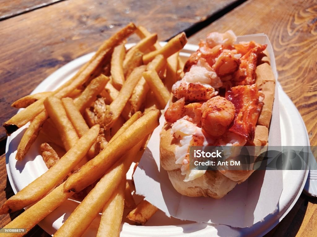 Fresh Maine Lobster Roll A fresh Maine lobster roll, stuffed with big chunks of claw meat, pictured with sides of fries and other garnishes. Foodie Stock Photo