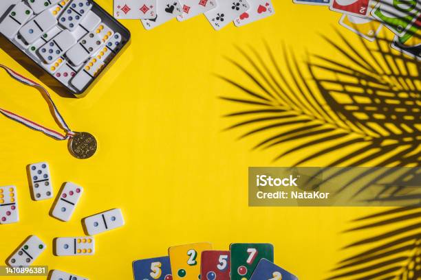 White Dominoes Playing Cards Uno Ligretto And Winner Medal On Yellow Background Board Game Stock Photo - Download Image Now