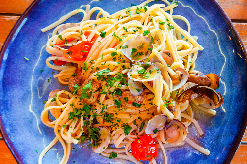 A plate with linguini with vongole and cherry tomatoes.