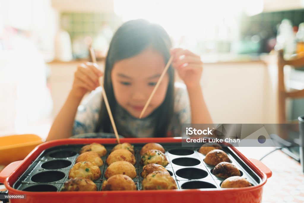 Home made Takoyaki Asian girl cooking octopus ball (Tokoyaki) at home. Takoyaki Stock Photo