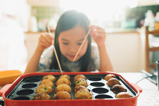 Home made Takoyaki Asian girl cooking octopus ball (Tokoyaki) at home. cooking takoyaki is a ball shaped japanese snack stock pictures, royalty-free photos & images