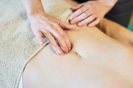 Close-up of a pelvic floor massage on the navel. Abdominal scar. Postpartum massage